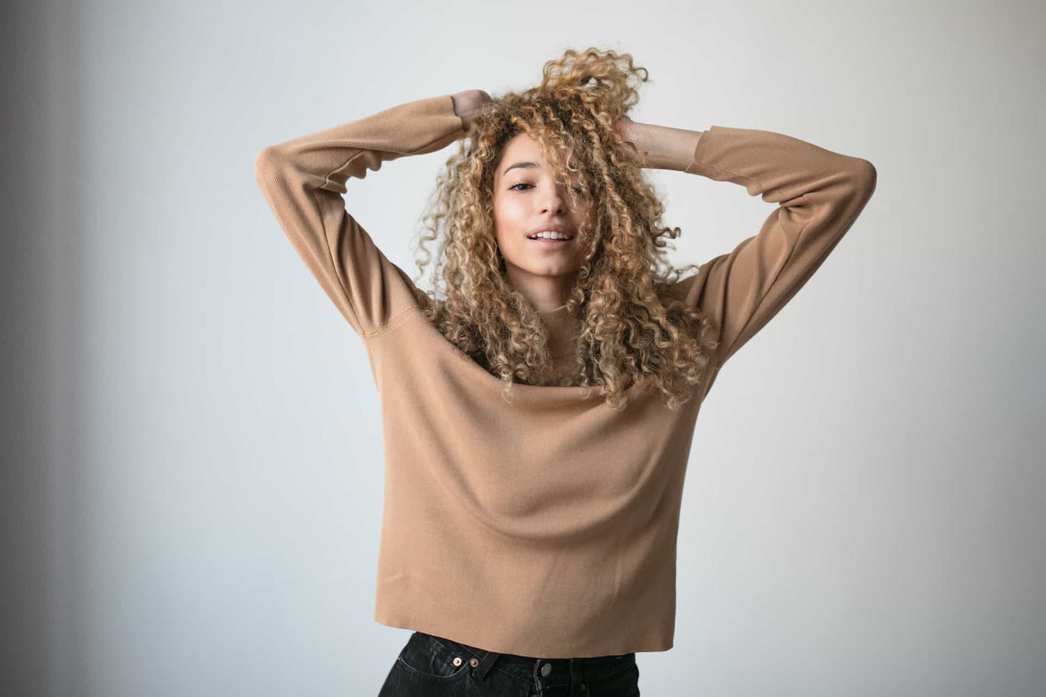 ragazza dal tono di pelle scuro si passa le mani tra i capelli color biondo cenere